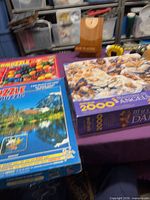 Three puzzle boxes on table: Angels, marbles, landscape