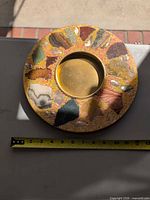 Full view of round stone and shell inlay tray with brass insert and tape measure showing diameter