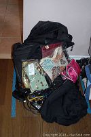 Assorted tote bags piled together showing variety, including black and patterned bags and some cords.