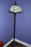 Full view of the UPS floor lamp showing stained glass shade with number 88 and dark metal pole standing against a purple wall.