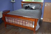 Assembled bed frame with slatted headboard and footboard, gray bedding front view