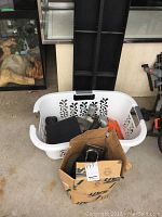 Overall view of the plastic basket containing drills and bits, with a cardboard box of castor wheels nearby.