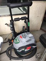 Side angle of the All Around Plus Shop Vac connected to its hose with the car bike rack in the background.