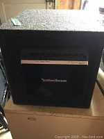 Front side of carpeted subwoofer enclosure showing Rockford Fosgate Punch branding plate