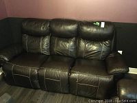 Front view of black three-seat faux leather sofa with visibly cushioned back and seats.