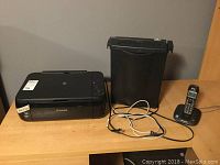 Photo of the Canon Pixma multifunction printer, paper shredder, and Panasonic cordless phone on a wooden surface.