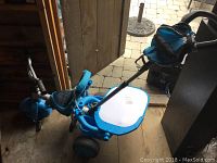 Blue Little Tykes child push trike with back push handle, padded seat, and storage compartment with white lid.