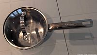 Top view of saucepan with lid showing interior and strainer holes
