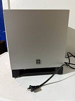 Front view of Yamaha subwoofer showing silver face and attached power cord