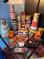 Group shot of entire assortment of tins on two-tier glass table