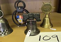 Group of three bells: Liberty Bell, brass ship-wheel bell, partial view silver bell