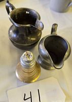 Top view of two metal creamers and one ribbed shaker