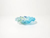 Full view of small blue fused glass ruffled plate on white background