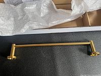 Brushed gold towel bar removed from packaging showing full length and mounting bases