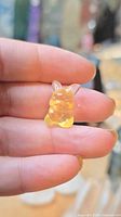 Front view of yellow fluorite Pikachu figurine held between fingers