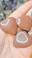 Group of goldstone heart cabochons on hand showing front surfaces and sparkle