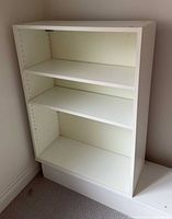 Front view of white bookcase showing three shelves and overall condition