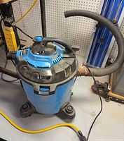Full view of blue DuraVac wet/dry vacuum with hose and casters