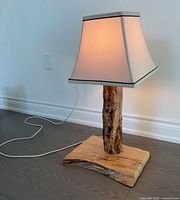 Full view of lamp lit, showing shade, wood post, base and cord