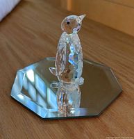 Profile view of crystal penguin on mirrored octagonal base
