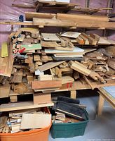 Pile of assorted wood pieces on shelving with tub below