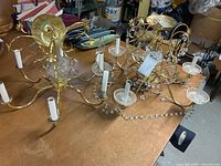 Both brass-tone chandeliers side by side on table
