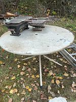 Top view of round steel patio table showing umbrella hole and paint wear
