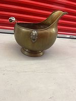 Side view showing overall form, lion head mount, spout, pedestal foot