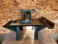 Overall lot showing boxed Craftsman router centered on router table with attachments at sides