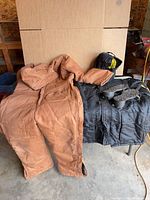 Overview of coveralls, jacket and cleats on table