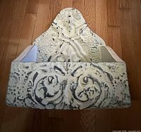 Front view of embossed metal wall pocket showing decorative pattern and open pocket