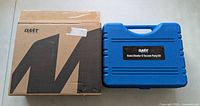 Closed blue carrying case beside original OMT box