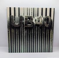 Front jacket showing UB40 raised lettering on striped background