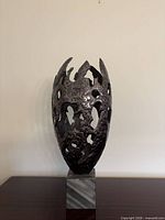 Full view of bronze abstract sculpture on grey stone base