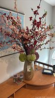 full view of ceramic vase with faux flowers on table