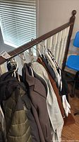 Group of clothing items hanging on railing: puffer, coats, shirts