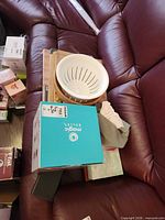Stacked items show Magic Bullet box, white plastic colander, wooden bowl, cutting board