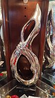 Front view of silver ceramic abstract sculpture on black base
