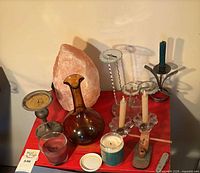 All items grouped on red surface showing salt lamp, decanter, candle holders, candles, knife