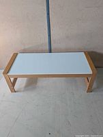 Full view of rectangular coffee table showing light wood frame and white top