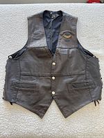 Front view of black leather vest showing snaps, pockets and chest badge