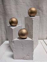 Front view of three plaster holders with gold candles