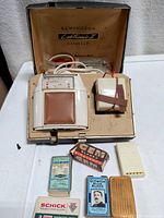 Open Remington Lectronic II cordless shaver in carry case with charger, brass blade case and assorted blade packs displayed