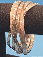 Six interlinked silver-tone bangles showing concentric circle and brick textures