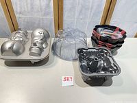All three cast aluminum cake pans, plastic domes and packaging displayed