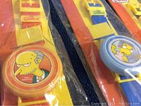 Close-up image showing a yellow and red band digital watch with Mr. Burns character on the face, sealed in original packaging.