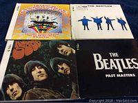 Four Beatles CDs laid out flat showing album covers: Magical Mystery Tour, Help!, Rubber Soul, and Past Masters.