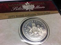 Front of the coin in packaging showing the 1971 British Columbia Silver Dollar with coat of arms and date range 1871-1971.