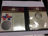 Photo of the open presentation booklet displaying the coin on the right side and informational text on the left about the 1978 Commonwealth Games Silver Dollar.