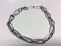 Full image of the sterling silver bracelet laid flat to show the unique open link design and lobster clasp.